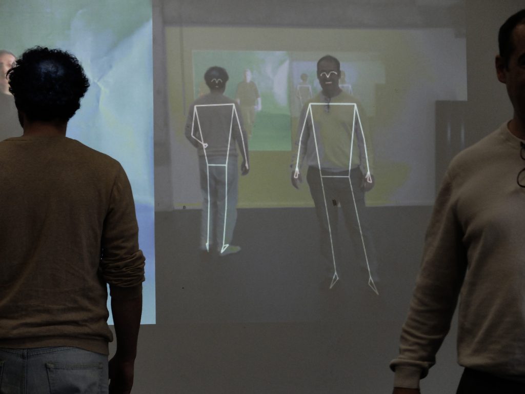 articipant standing in front of a projected image showing body outlines during the AI-SECRETT workshop in Antwerp